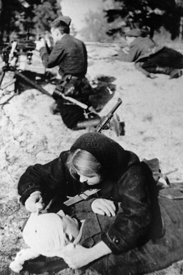 A nurse bandaging a wounded guerrilla
