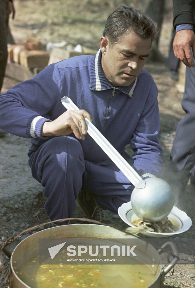 Cosmonaut Nikolayev pouring out fish soup at a fishing trip 