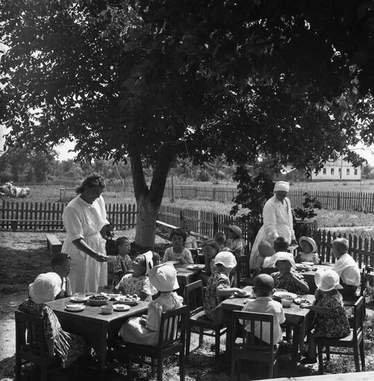 Children at breakfast in the garden of the Budyonnov collective farm