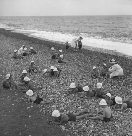 Children in charge of child-minders take rest on shore of Black Sea