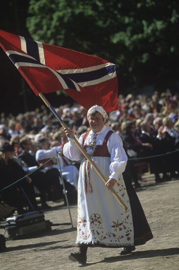 Norwegian woman wearing national dress and carrying a flag