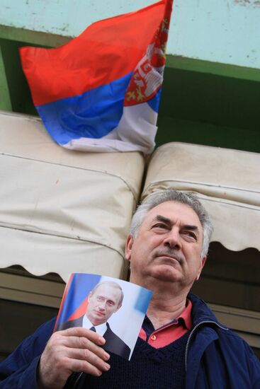 A man holding a portrait of Vladimir Putin