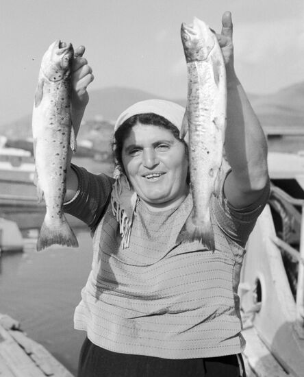 A woman showing a trout she has caught