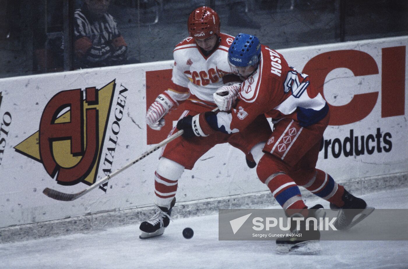 Hockey players grappling for puck at board
