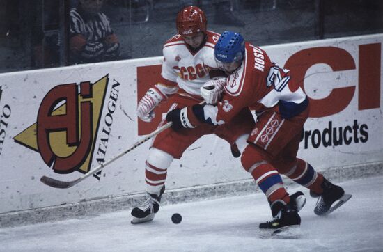 Hockey players grappling for puck at board