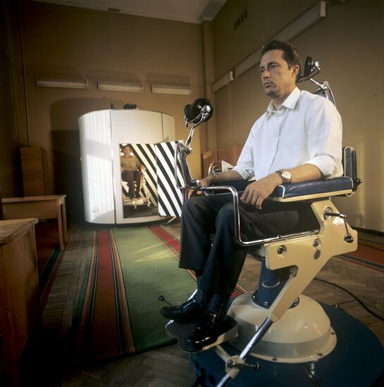 Onboard engineer Vladimir Aksyonov of spaceship Soyuz-22 undergoing medical training of his vestibular organ. Seen in the background is Valery Bykovsky, pilot-cosmonaut of the USSR and Hero of the Soviet Union