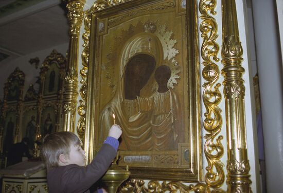 A boy in front of the icon of the Virgin