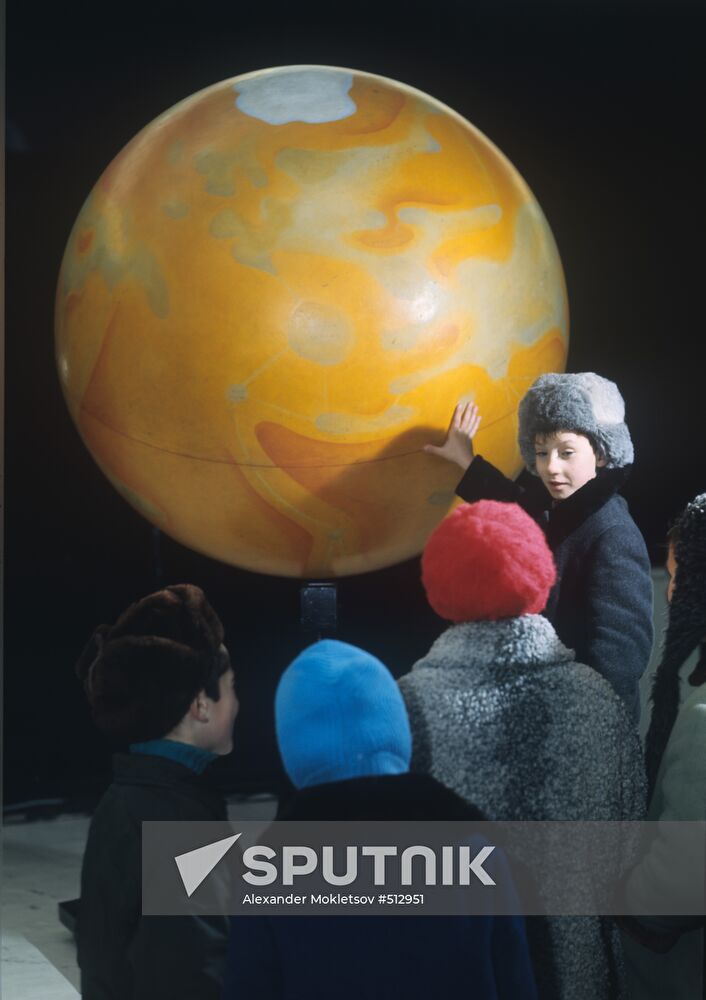 Schoolchildren at the terrestrial globe of Mars