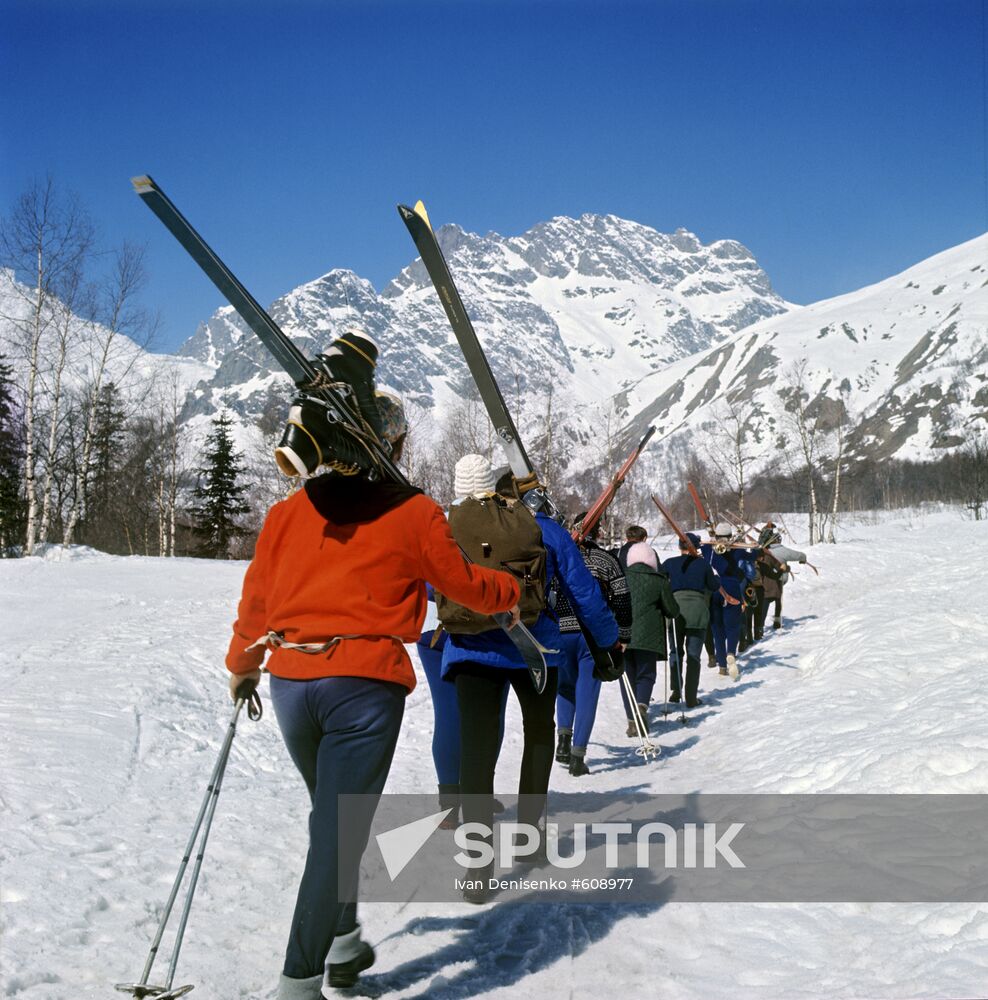 Alpine skiers going to piste