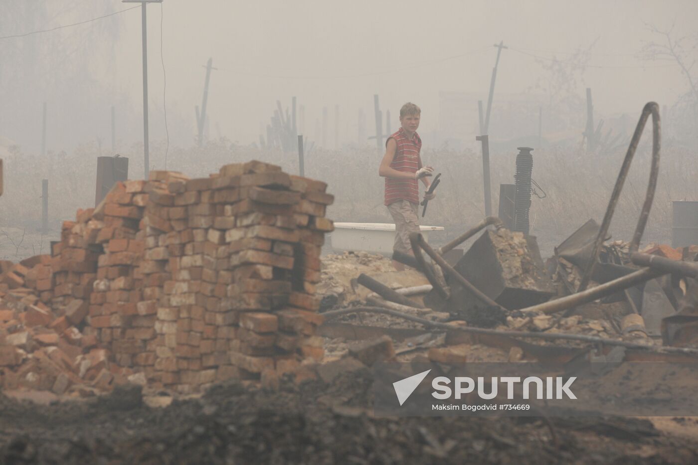A resident of the village of Borkovka, Nizhny Novgorod Region, clearing the debris. Location: Russia, Nizhny Novgorod region. Author: Maksim Bogodvid/Sputnik. Aftermath of fire in village of Borkovka