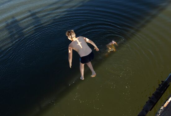 Boys jump off pedestrian bridge over Teza River in Shuya