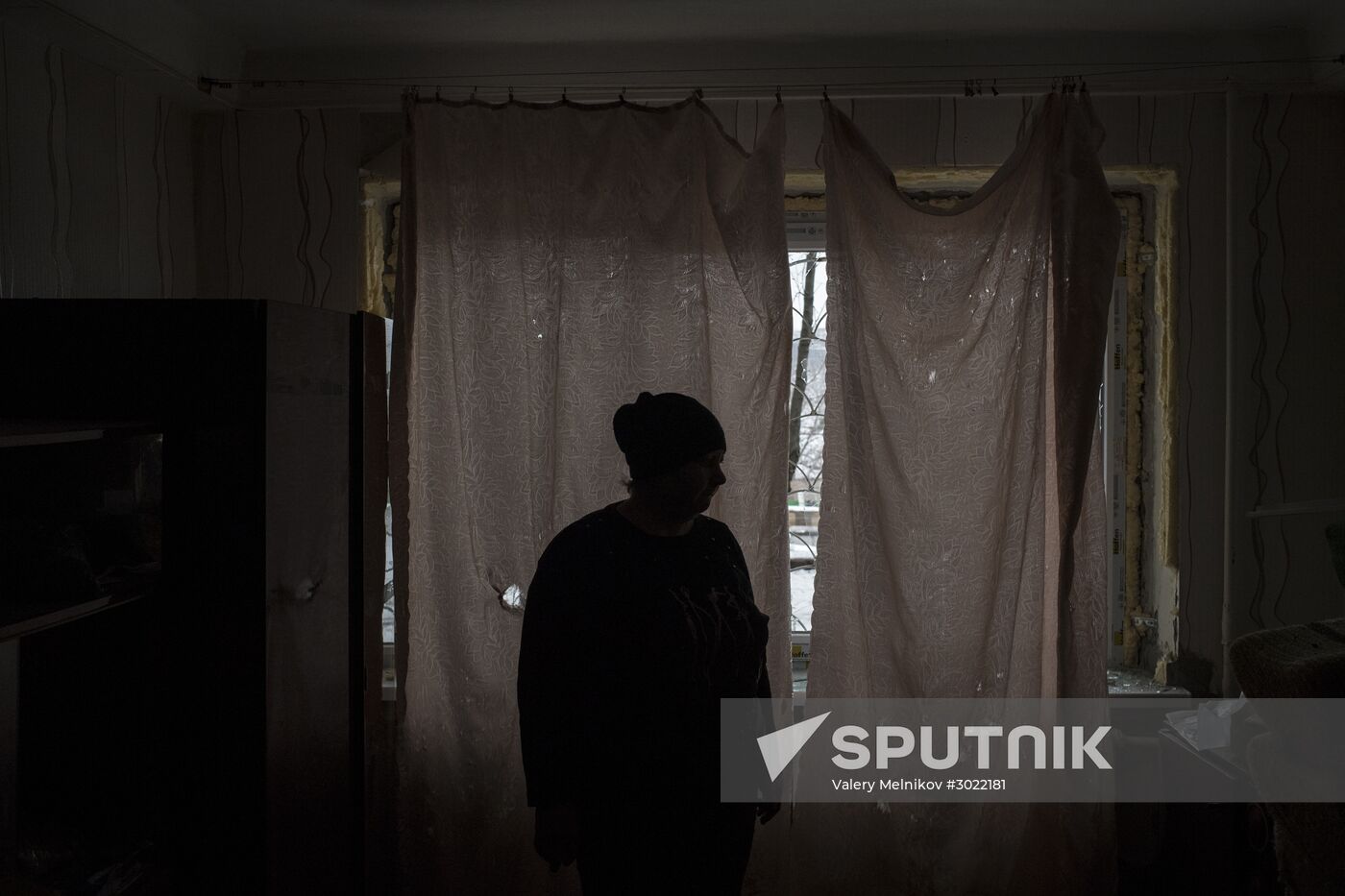 A woman near a window damaged during shelling and covered with cloth, in Donetsk's Kiyevsky district. Location: Ukraine, Donetsk. Author: Valery Melnikov/Sputnik. Donetsk update