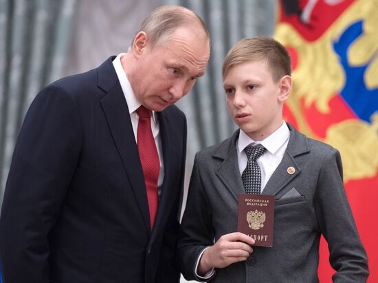 Russian President Vladimir Putin presents passports to young Russian citizens on Russia Day