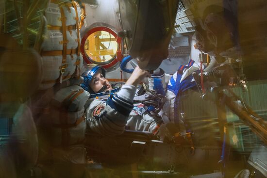 Soyuz TMA-14M crew members inspect spacecraft and try on their space suits