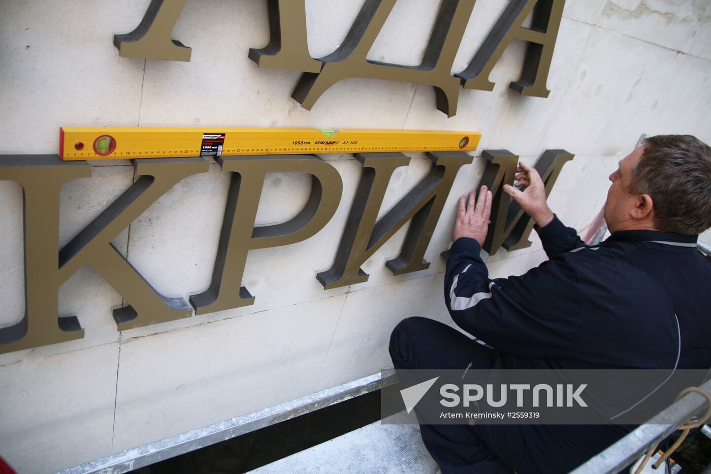 Workers attach Ukrainian sign to facade of State Council of Crimea