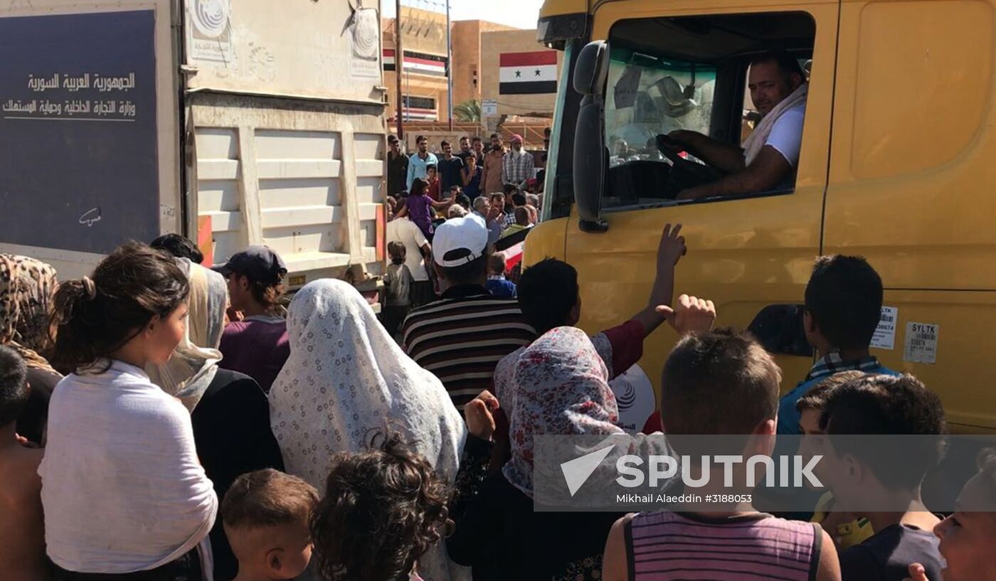 Deir ez-Zor residents welcome a truck convoy of medicines and food