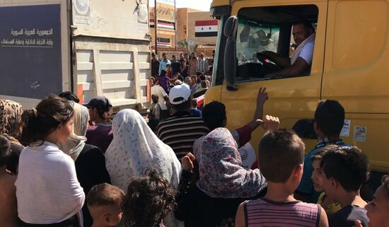 Deir ez-Zor residents welcome a truck convoy of medicines and food