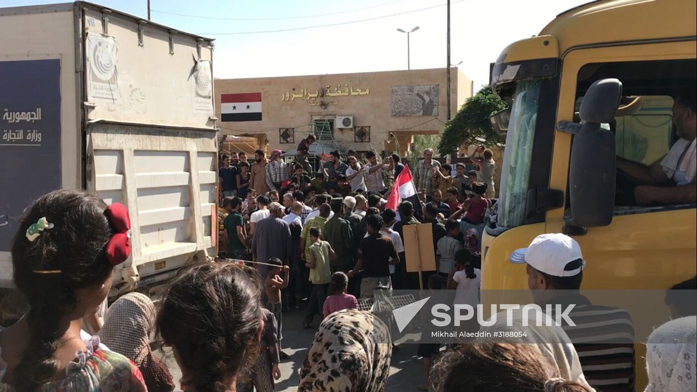 Deir ez-Zor residents welcome a truck convoy of medicines and food