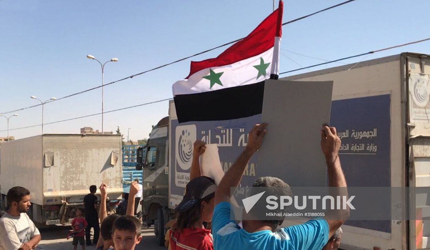 Deir ez-Zor residents welcome a truck convoy of medicines and food