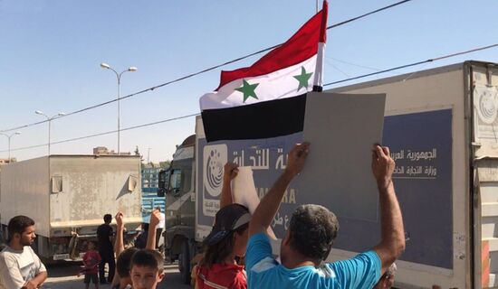 Deir ez-Zor residents welcome a truck convoy of medicines and food
