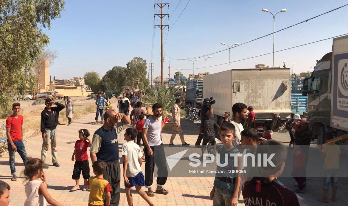 Deir ez-Zor residents welcome a truck convoy of medicines and food