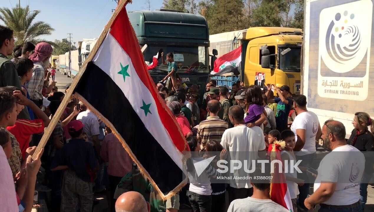 Deir ez-Zor residents welcome a truck convoy of medicines and food
