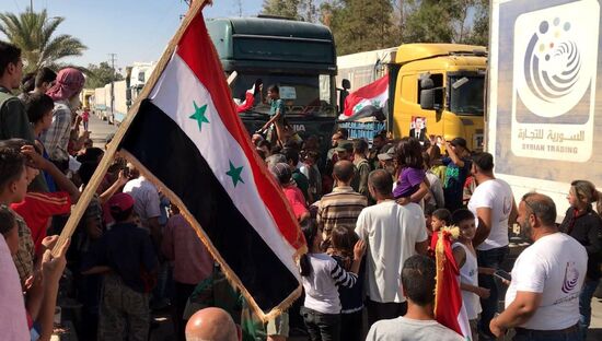 Deir ez-Zor residents welcome a truck convoy of medicines and food