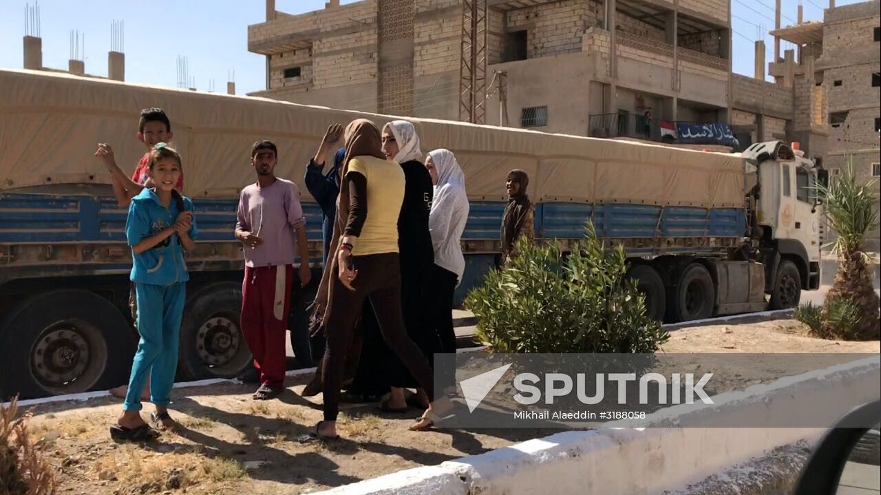 Deir ez-Zor residents welcome a truck convoy of medicines and food
