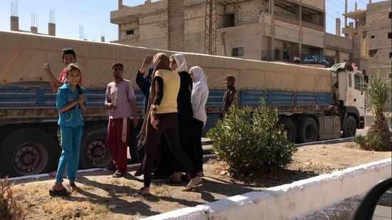 Deir ez-Zor residents welcome a truck convoy of medicines and food