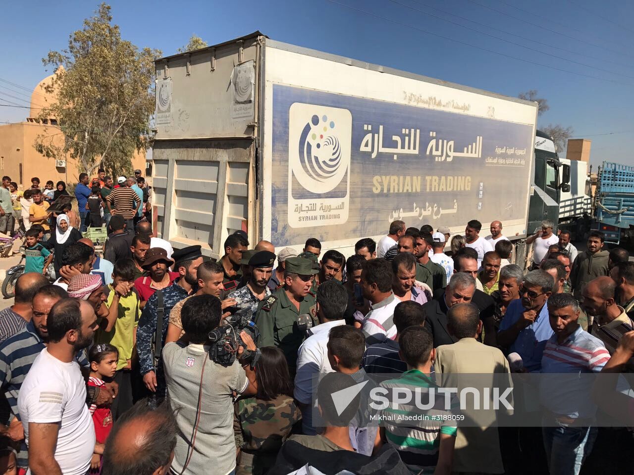 Deir ez-Zor residents welcome a truck convoy of medicines and food