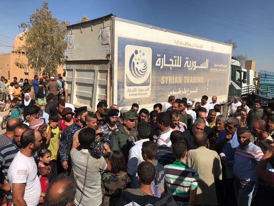 Deir ez-Zor residents welcome a truck convoy of medicines and food