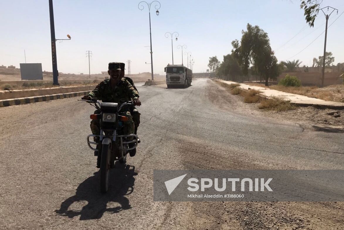 Deir ez-Zor residents welcome a truck convoy of medicines and food