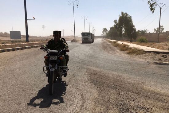 Deir ez-Zor residents welcome a truck convoy of medicines and food