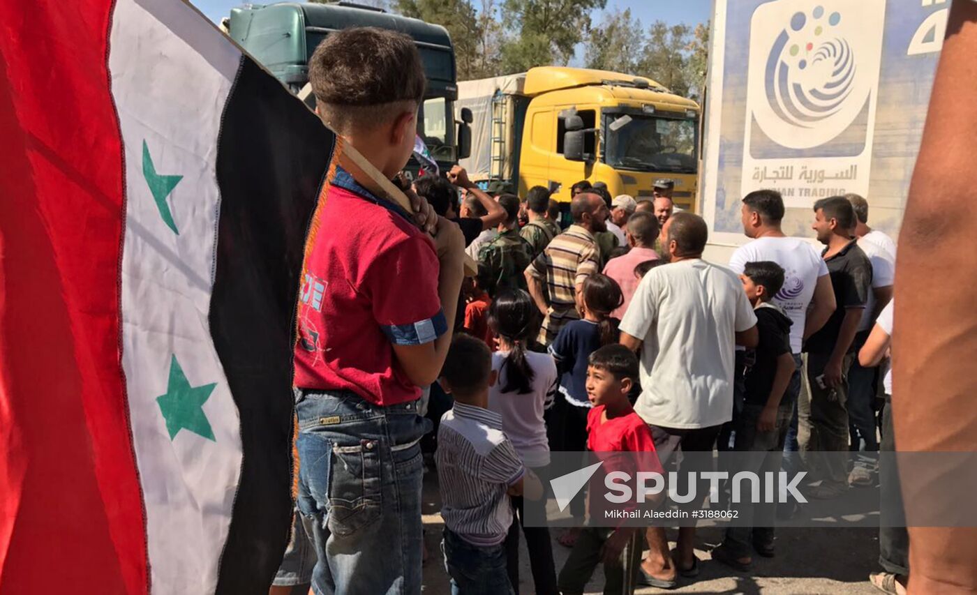 Deir ez-Zor residents welcome a truck convoy of medicines and food