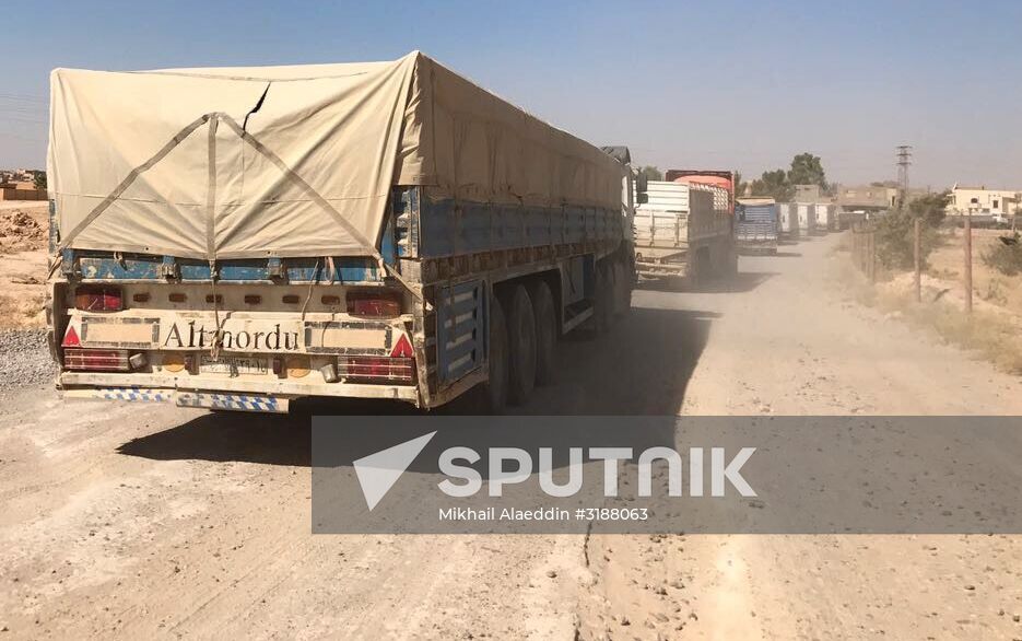 Deir ez-Zor residents welcome a truck convoy of medicines and food