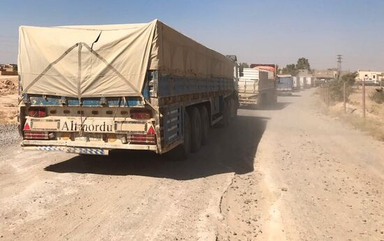 Deir ez-Zor residents welcome a truck convoy of medicines and food