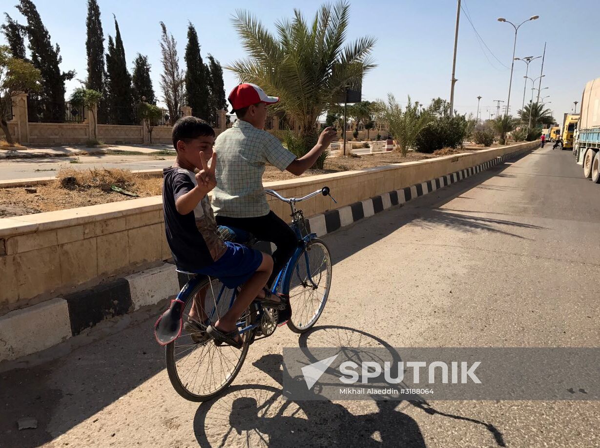 Deir ez-Zor residents welcome a truck convoy of medicines and food