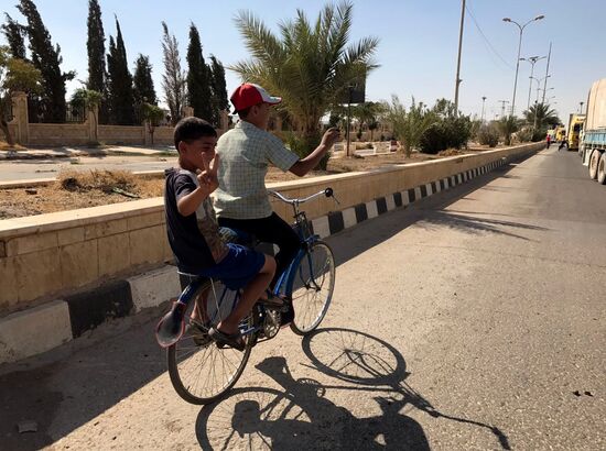 Deir ez-Zor residents welcome a truck convoy of medicines and food