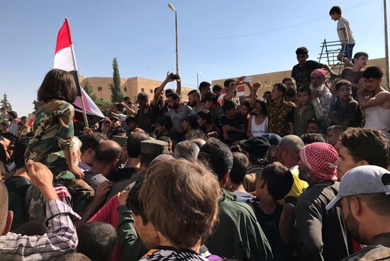 Deir ez-Zor residents welcome a truck convoy of medicines and food