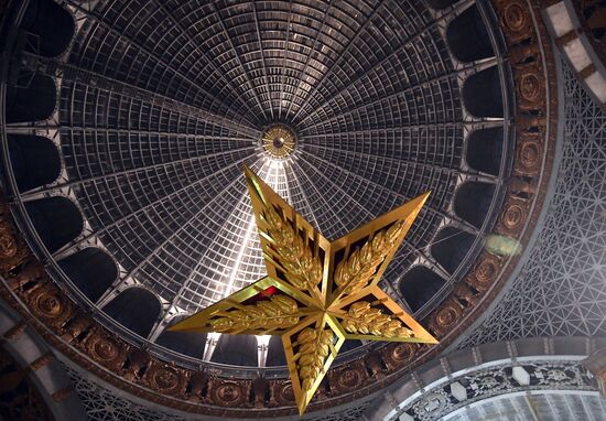 Installing star-shaped chandelier in Cosmos pavilion at VDNKh