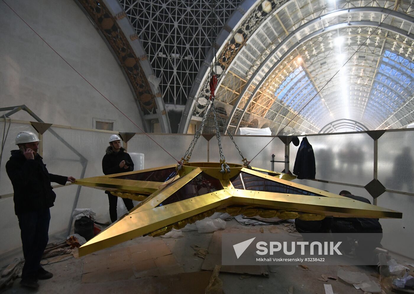 Installing star-shaped chandelier in Cosmos pavilion at VDNKh