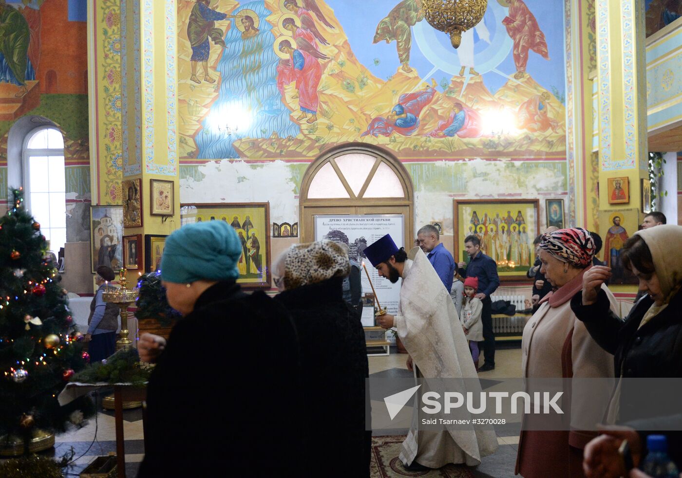 Father Sergius, the priest, center, and parishioners during a Christmas liturgy at the Cathedral of Saint Michael the Archangel in Grozny. Location: Russia, Chechen Republic, Grozny. Author: Said Tsarnaev/Sputnik. Christmas celebrated across Russia