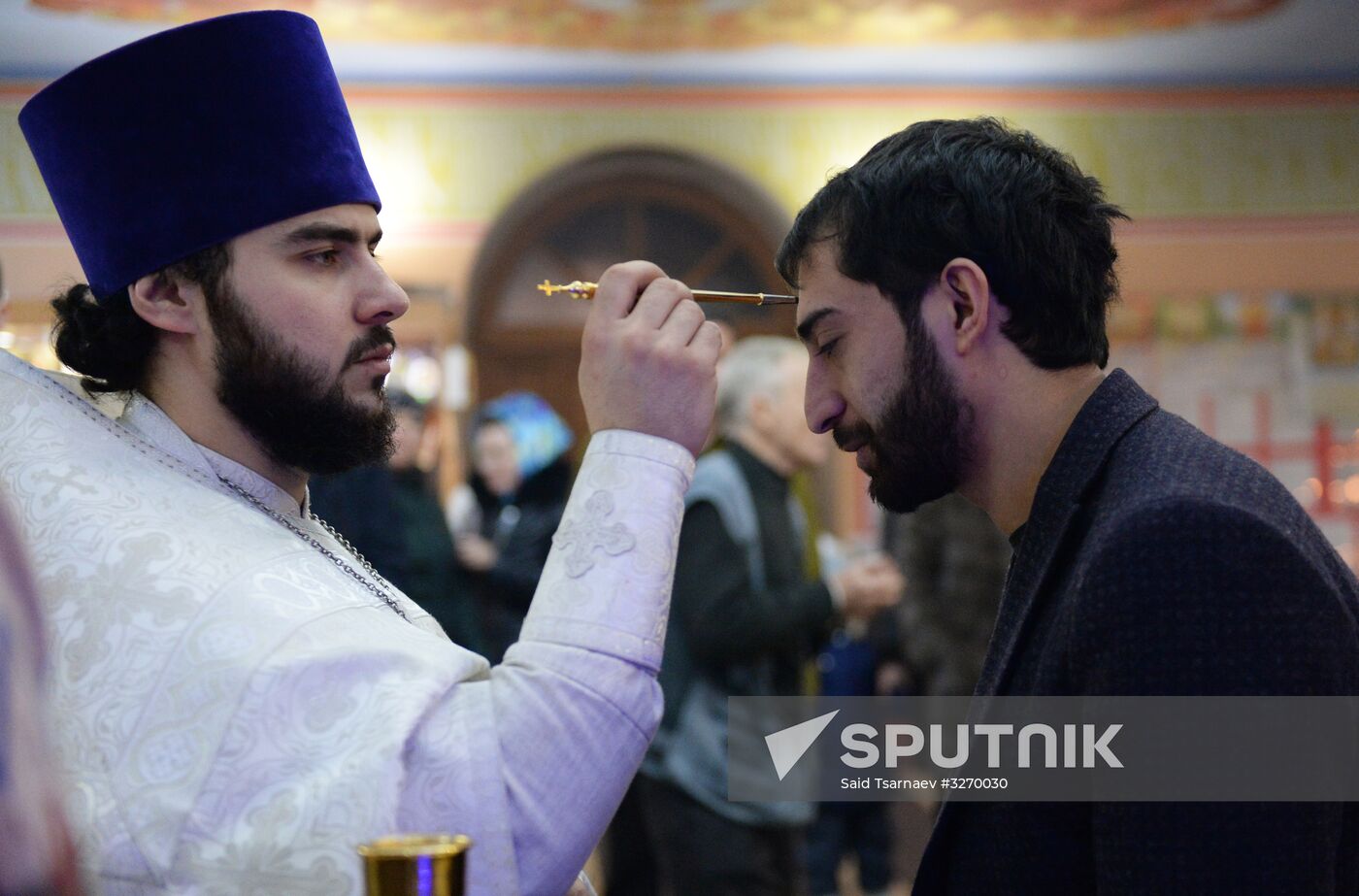 Father Sergius, the priest, center, and a parishioner during anointment at a Christmas liturgy at the Cathedral of Saint Michael the Archangel in Grozny. Location: Russia, Chechen Republic, Grozny. Author: Said Tsarnaev/Sputnik. Christmas celebrated across Russia
