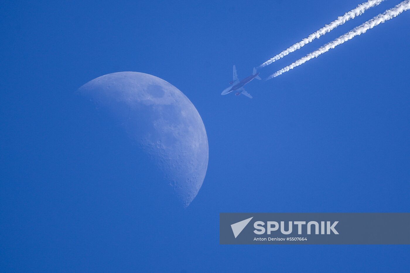 Airplanes fly in the sky with Moon visible