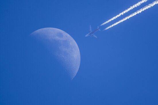 Airplanes fly in the sky with Moon visible