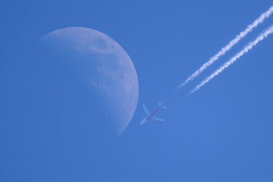 Airplanes fly in the sky with Moon visible