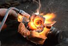 A metal rose, just made from a spent shell casing, glows from the heat of the burner at Victor Mikhalev's workshop in Donetsk, self-proclaimed Donetsk People's Republic, Eastern Ukraine. The Honored Master of Folk Art in the DPR, blacksmith Viktor Mikhalev, make arts from empty war shells. Location: Ukraine, Donetsk region, Donetsk. Author: Sergey Baturin. Ukraine DPR Folk Art