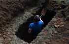 A participant digs a grave during the high-speed grave digging competition at Necropolis Siberia 2021 exhibition, in Novosibirsk, Russia. Participants must dig a grave 160 cm deep according with the size of the coffin presented. The speed and quality of work are assessed. Location: Russia, Novosibirsk. Author: Alexandr Kryazhev/Sputnik. Russia Necropolis Exhibition
