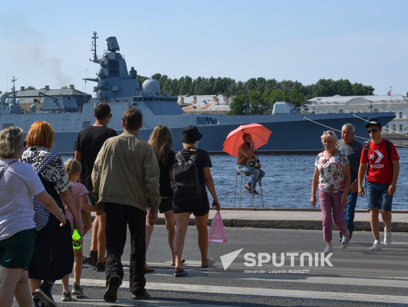 People cross the roadway in front of the Admiral Kasatonov Russian Navy frigate seen in the background, before the upcoming Russian Navy Day parade in St. Petersburg, Russia. Location: Russia, Saint Petersburg. Author: Alexander Galperin/Sputnik. Russia Navy Day Parade Rehearsal