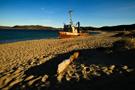 Corroded trawler on sandy beach in Teriberka